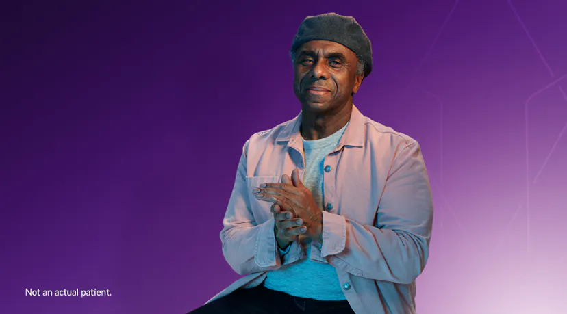 Smiling older man with his hands together wearing a gray cap