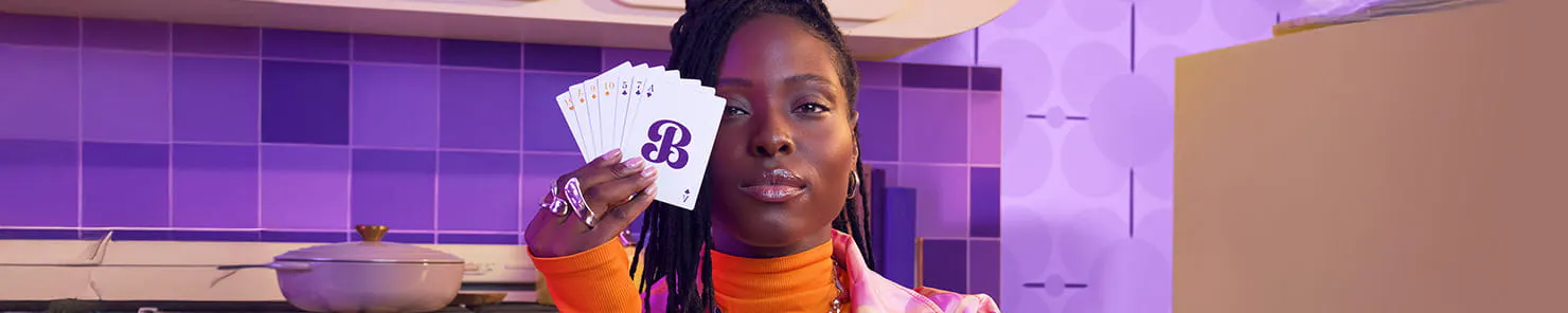 Woman holding playing cards with the letter B on them in front of her face