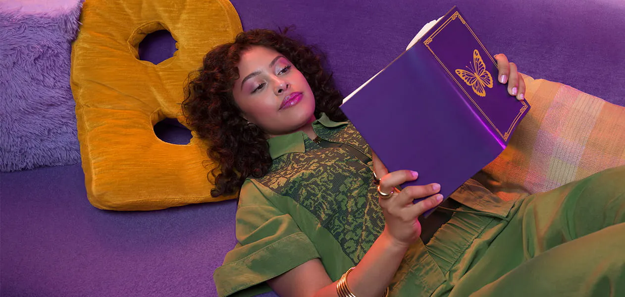 Woman lying on her back reading a purple book with a butterfly on the cover Woman lying on her back reading a purple book with a butterfly on the cover