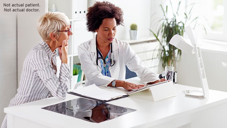 Woman with glasses talking to her doctor