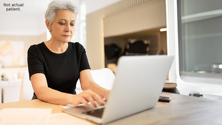 Woman sitting at a table working on her laptop