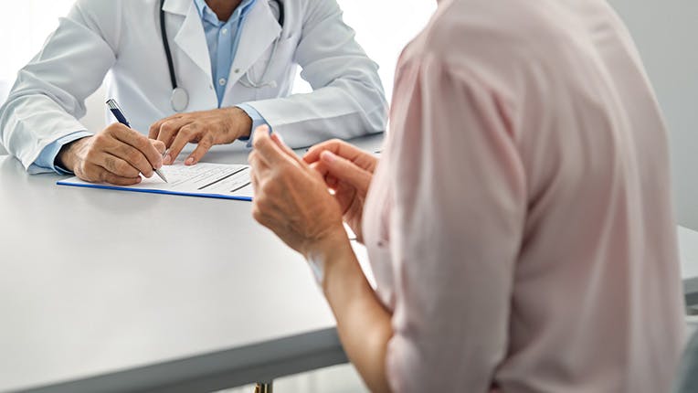 Doctor writing on a clipboard while talking to a woman