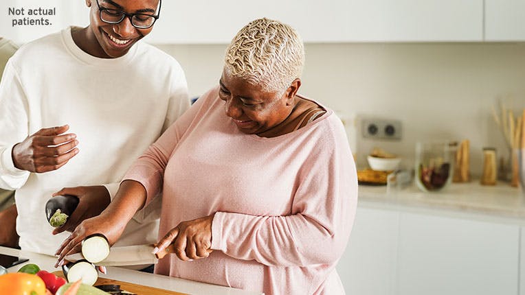 A woman and her grandson preparing vegetables in a kitchen