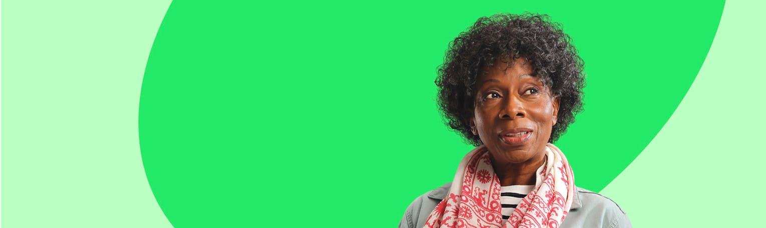 A black woman looking to the side wearing a grey coat and a red and white scarf.