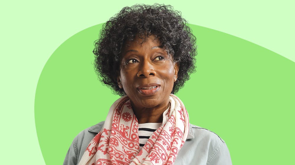 A black woman looking to the side wearing a grey coat and a red and white scarf. A black woman looking to the side wearing a grey coat and a red and white scarf.