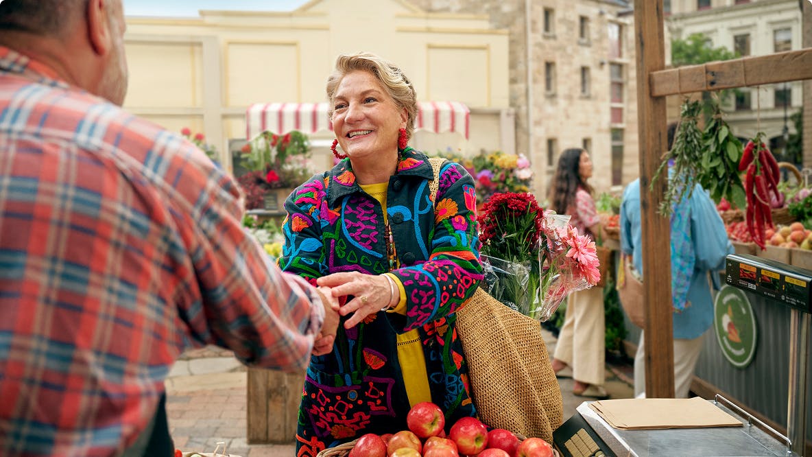 Woman shaking hands with man at outdoor farmers market