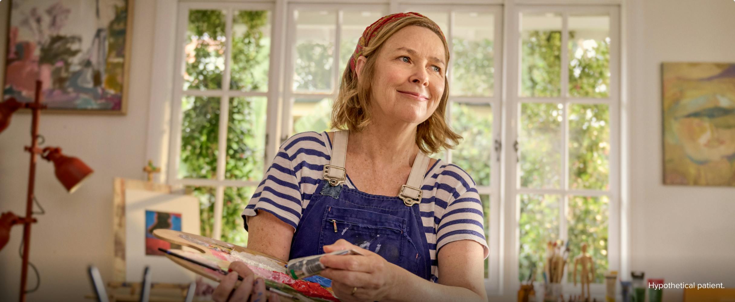 EGPA patient Meredith in studio holding paintbrush and palette EGPA patient Meredith in studio holding paintbrush and palette