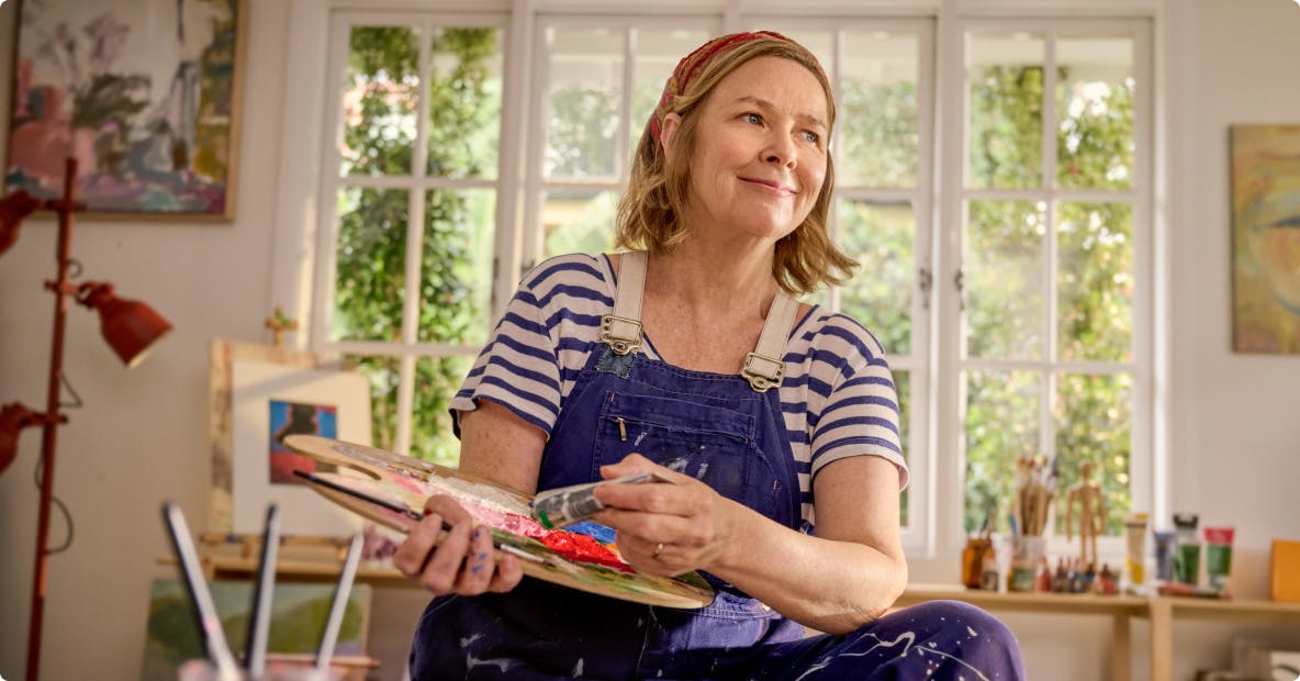 EGPA patient Meredith in studio holding paintbrush and palette