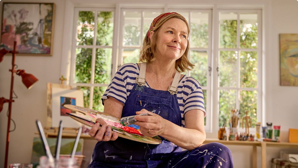 EGPA patient Meredith in studio holding paintbrush and palette