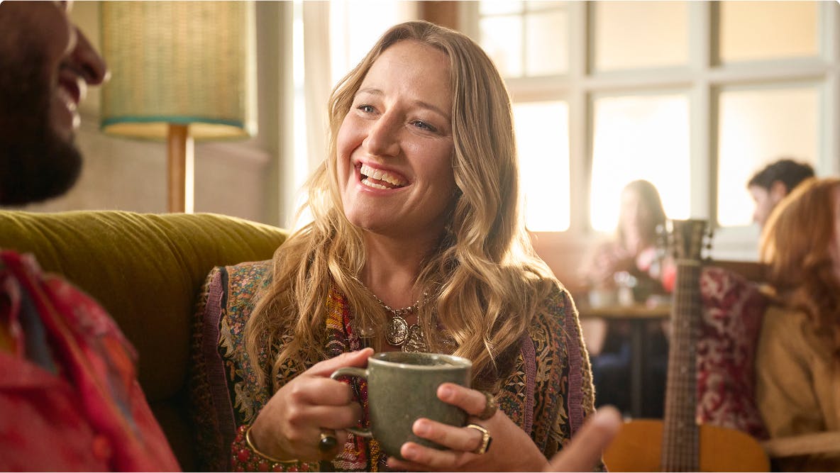 Nasal polyps patient Janet drinking coffee while talking to man on couch Nasal polyps patient Janet drinking coffee while talking to man on couch
