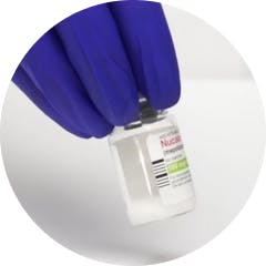 Gloved hand swirling NUCALA lyophilized powder vial