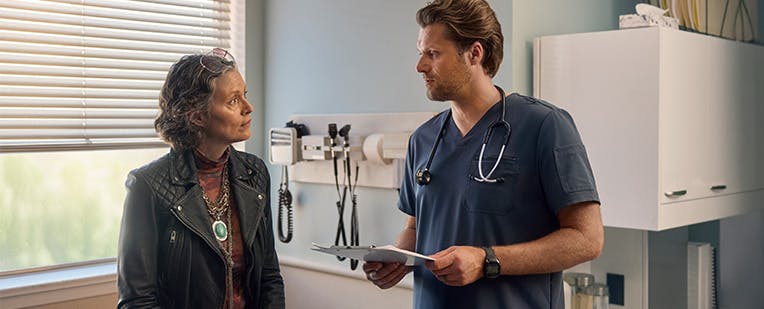 Older female patient talking to her doctor in an exam room Older female patient talking to her doctor in an exam room