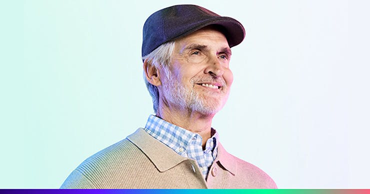 An older white male wearing a sweater over a blue checkered shirt and a brown hat.