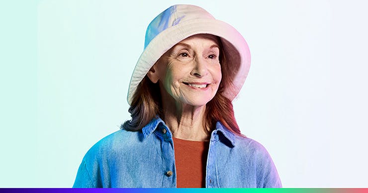 An older white woman wearing a bucket style hat and a denim shirt.