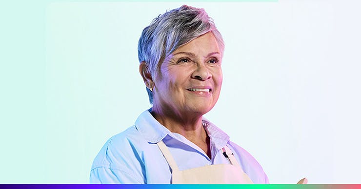 An older woman with gray hair wearing a blue collared shirt and an apron.