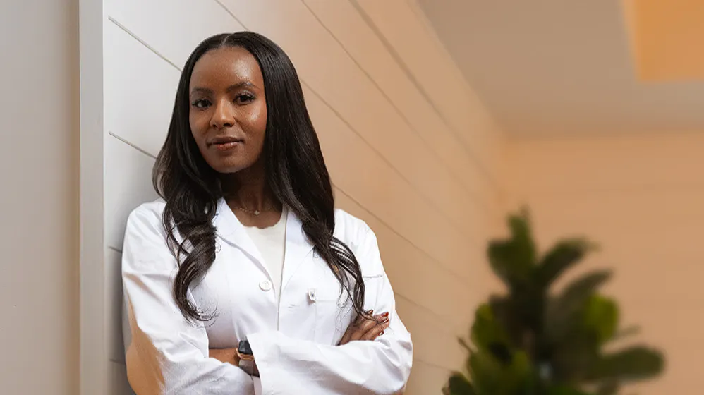 Dr. Kuria wearing a white lab coat with her arms crossed