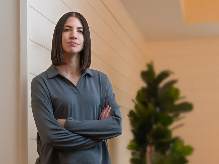Woman wearing a blue collared shirt with her arms crossed