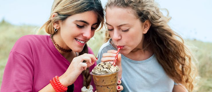 Two teens sharing an iced coffee