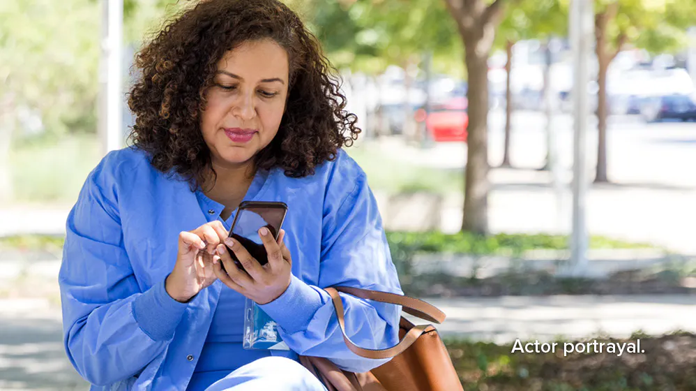 Actor portrayal: female nurse looking at her cell phone while sitting outside