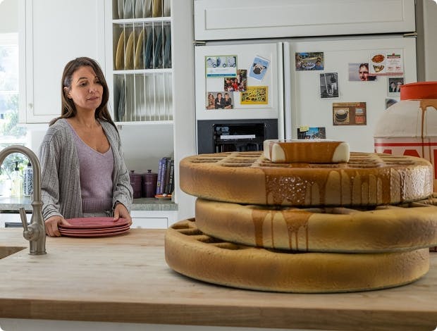 Woman in kitchen looking at a large-sized waffle