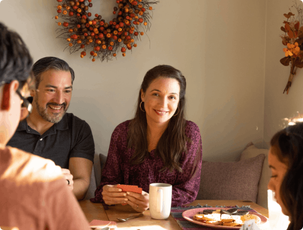 Smiling woman sitting at a table with her family while playing a card game