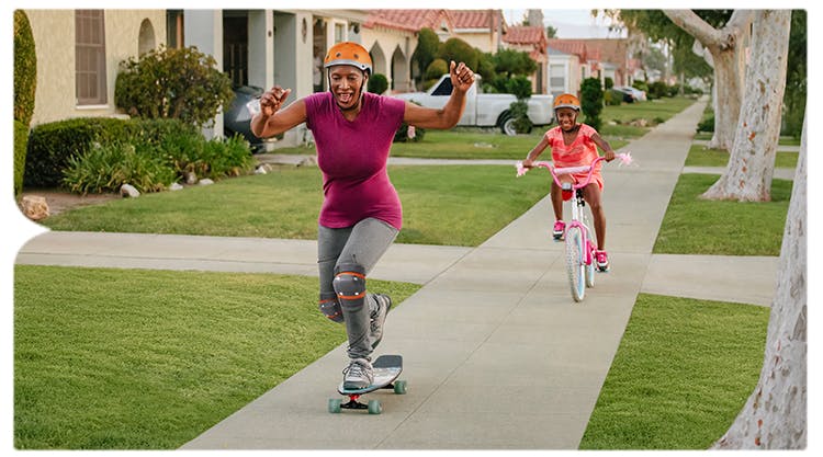 Adult immunization hero of woman skateboarding and daughter riding bike Adult immunization hero of woman skateboarding and daughter riding bike