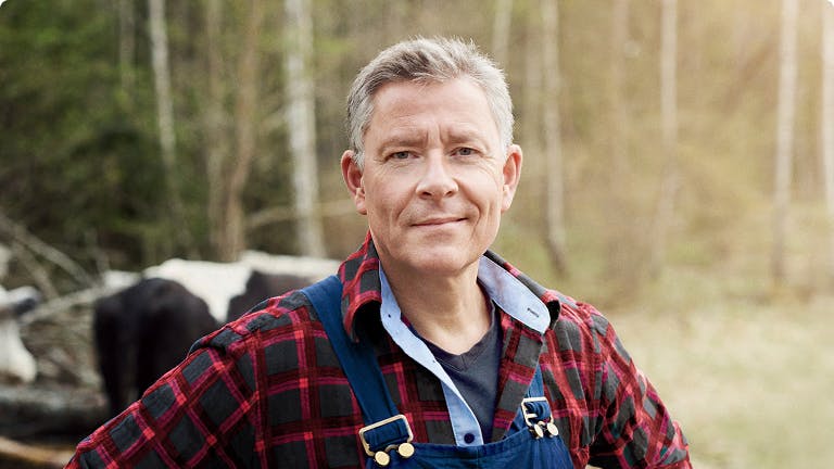 Nasal polyps patient Frank in flannel shirt and suspenders standing in front of cows