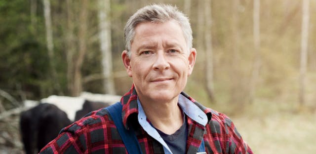 Nasal polyps patient Frank in flannel shirt and suspenders standing in front of cows