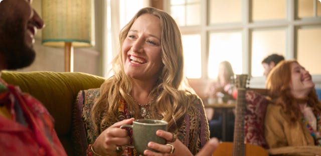 Nasal polyps patient Janet drinking coffee while talking to man on couch