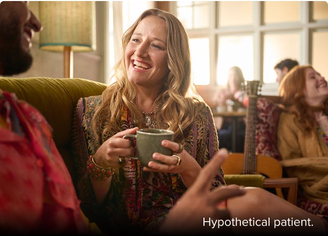 Nasal polyps patient Janet smiling at a friend on a couch in a coffee shop