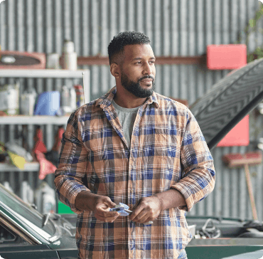 Asthma patient Craig standing in front of a car in an automotive workshop