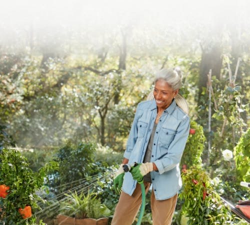 Image: Older woman smiling and watering garden