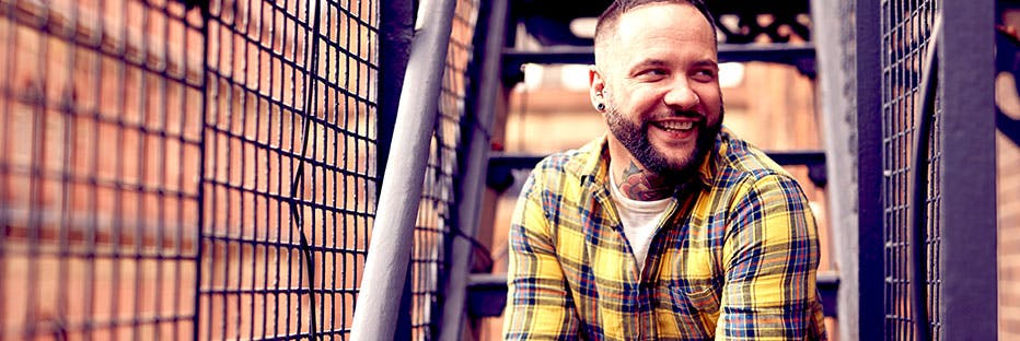 Smiling man with HIV wearing a plaid shirt