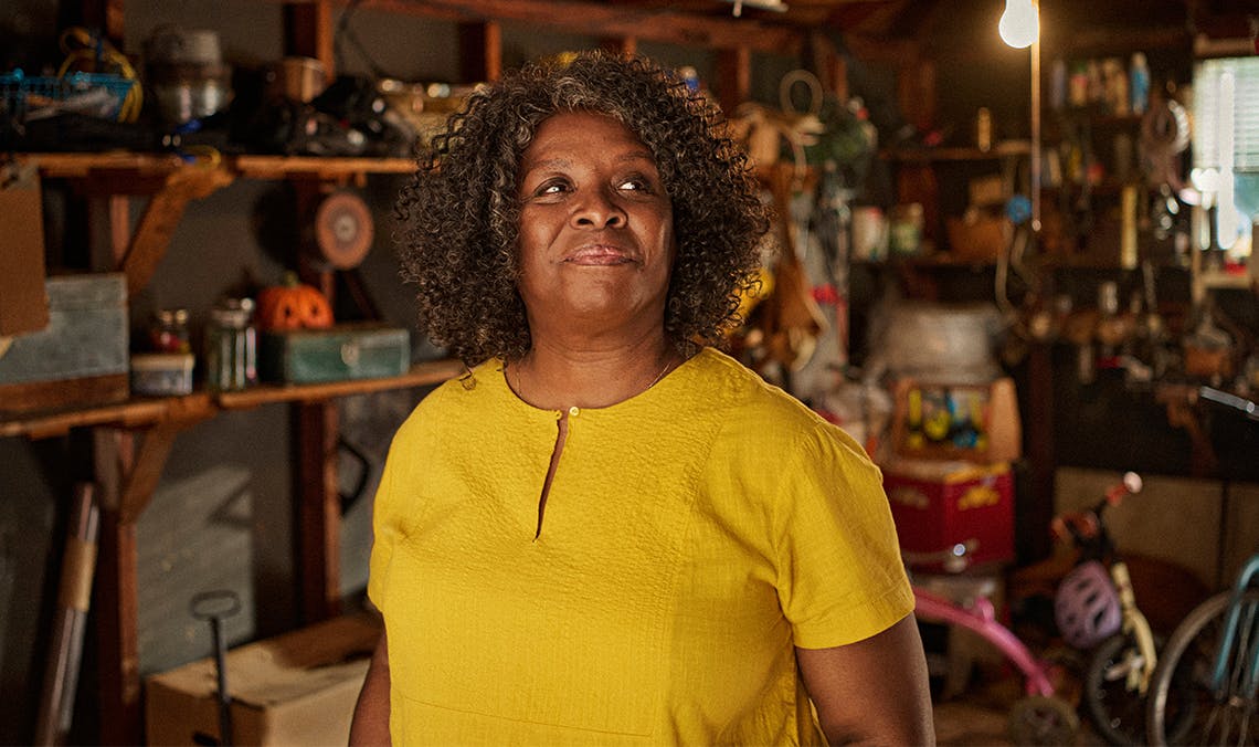 Woman in yellow shirt smiling in a workshop