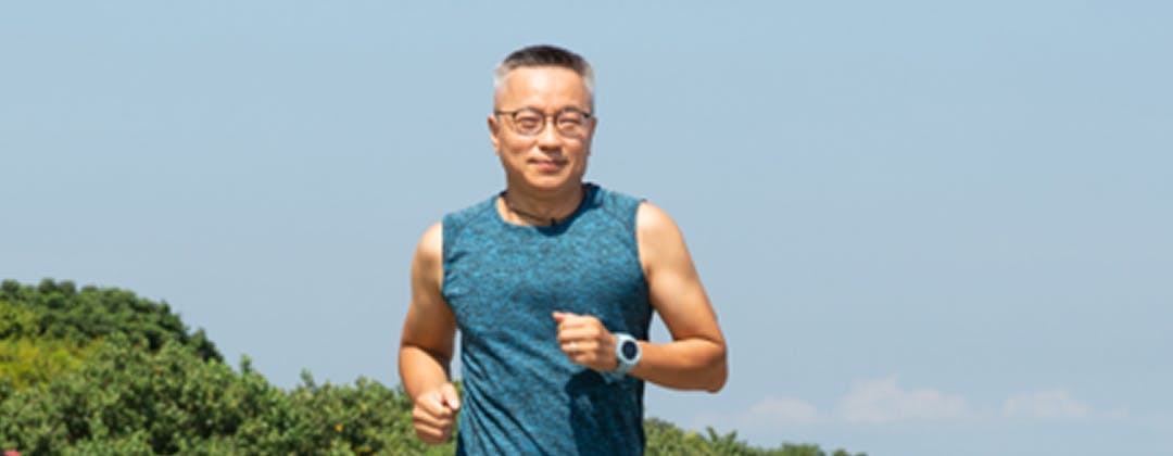 Man jogging with a background of blue sky and trees