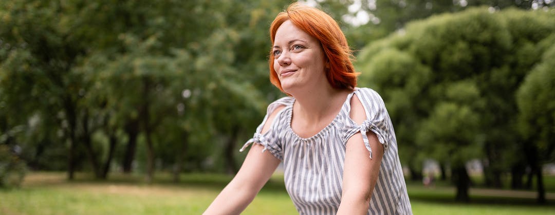 Red-haired woman riding a bike in the park