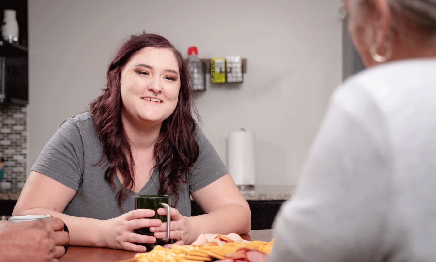 A young female caucasian talking with family over food