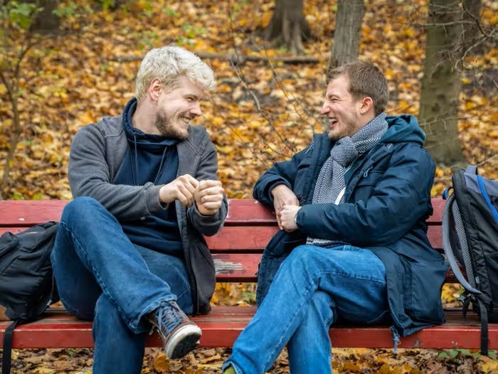 Two men sitting on a bench chatting and smiling in Hamburg