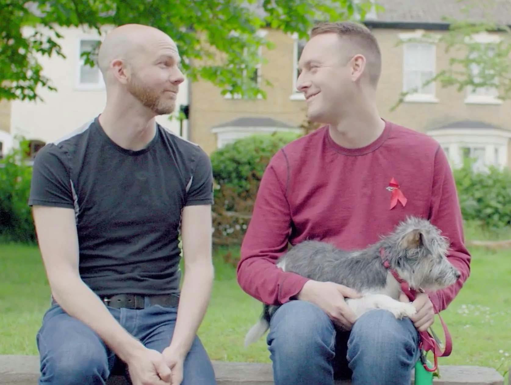 Two men looking at each other, one holding a dog