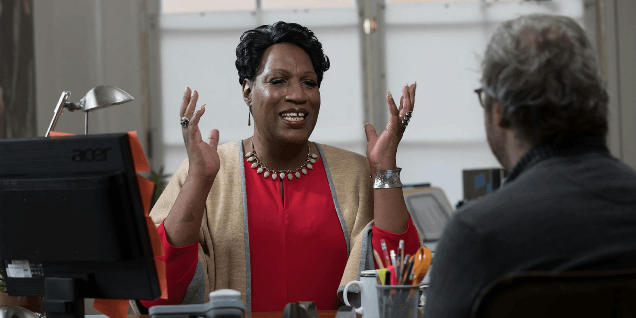 Woman is animated while talking to a man at her desk Woman is animated while talking to a man at her desk