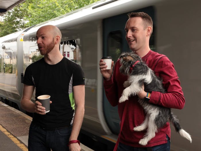 Two men drinking coffee at a train station