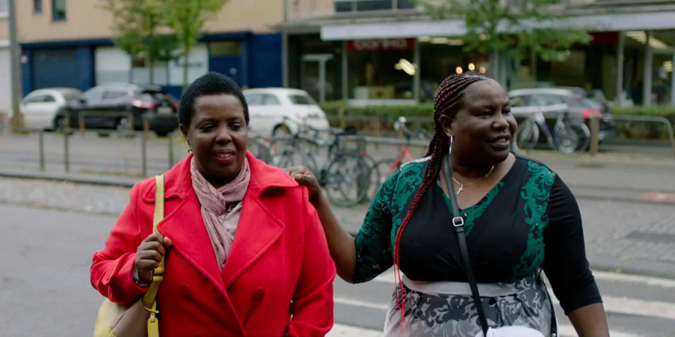 two women walking on street, one with hand on shoulder of other