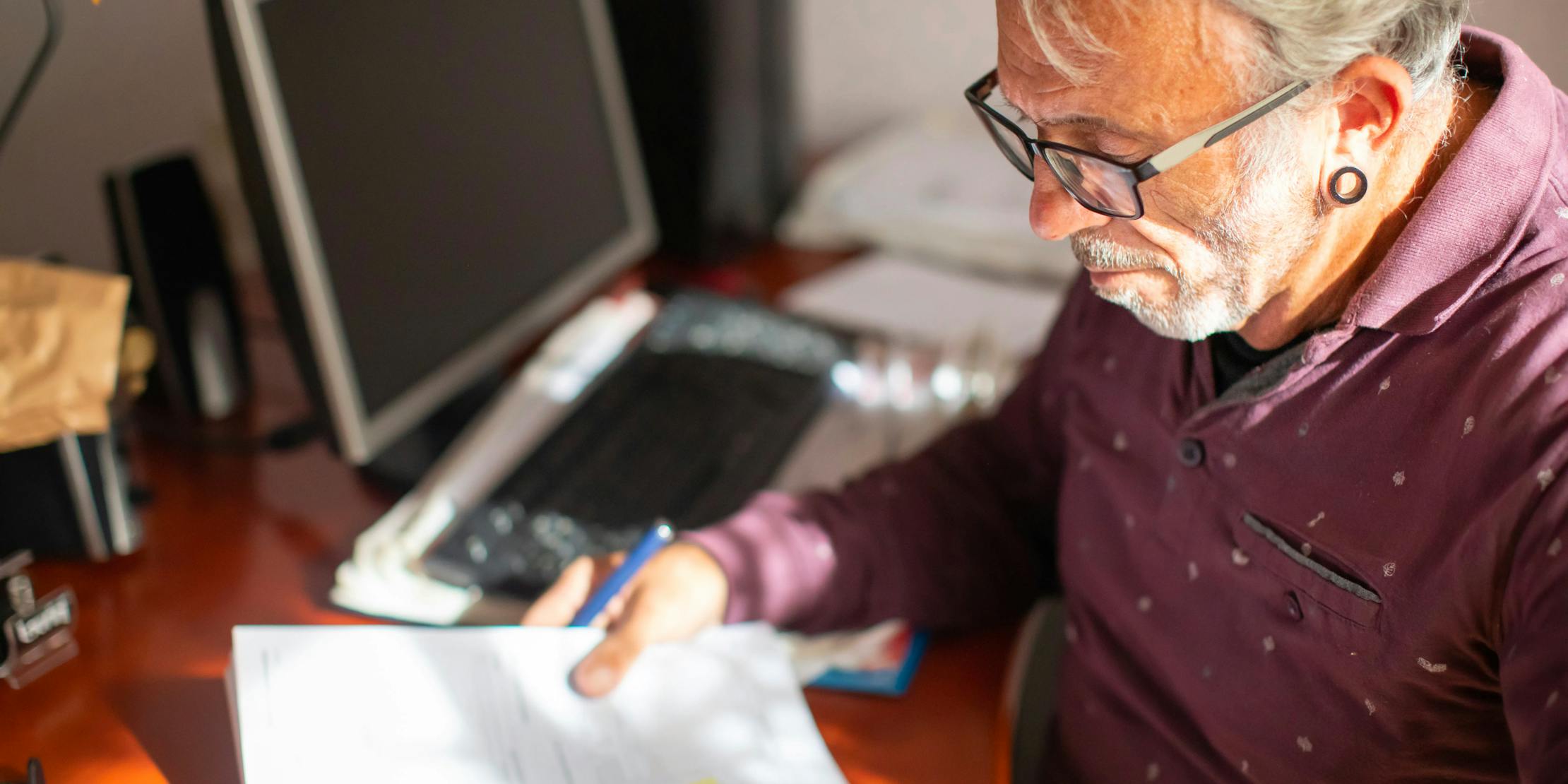 older man living with HIV sitting at a desk