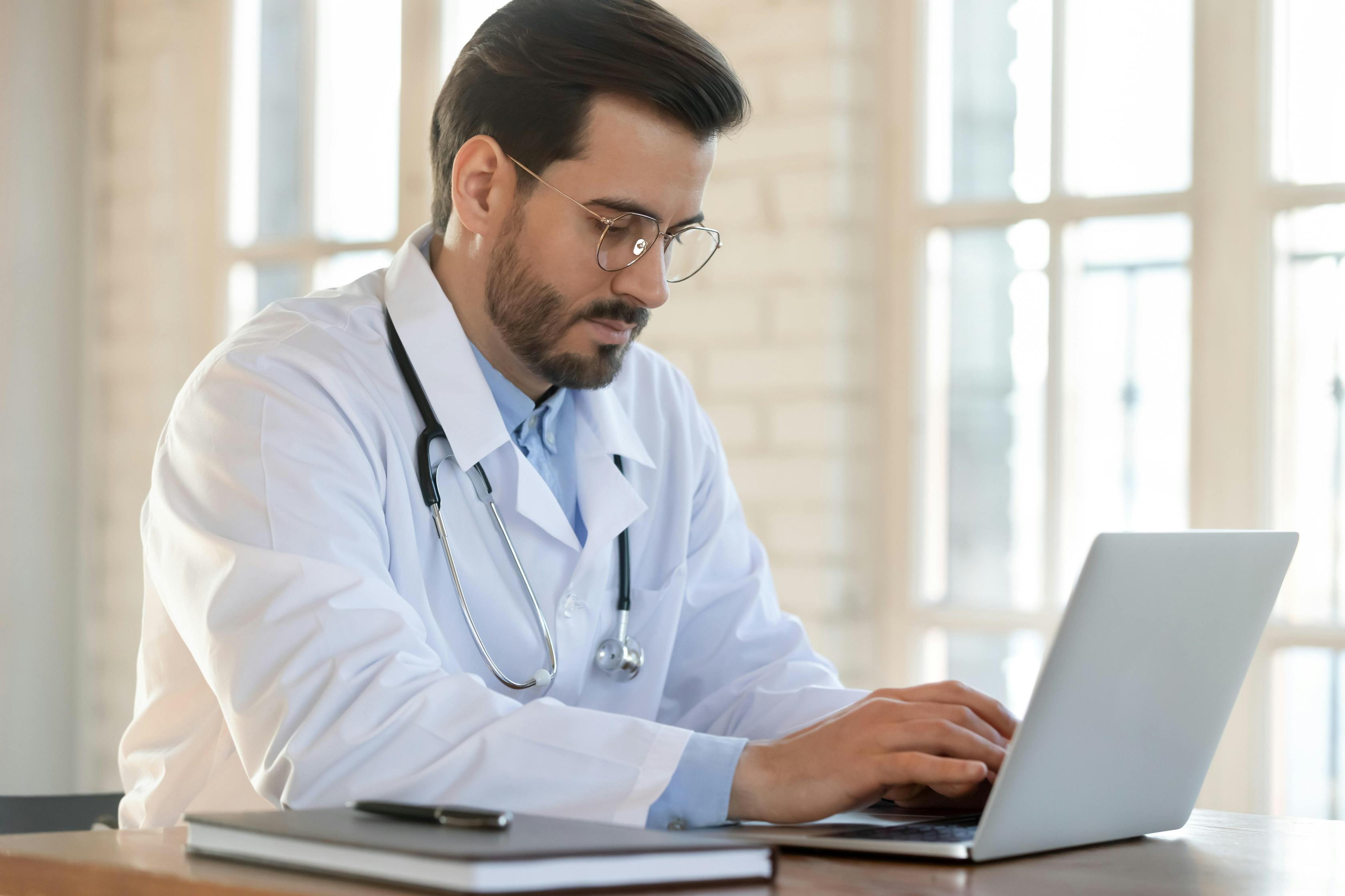 Doctor in white medical uniform sit at desk in hospital