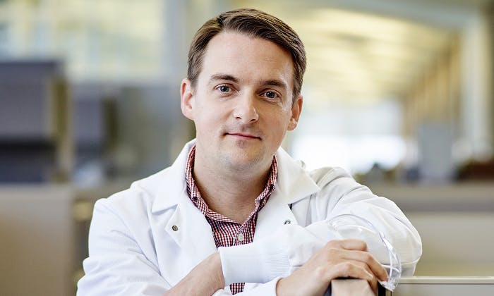 Person in white lab coat in an indoor setting.
