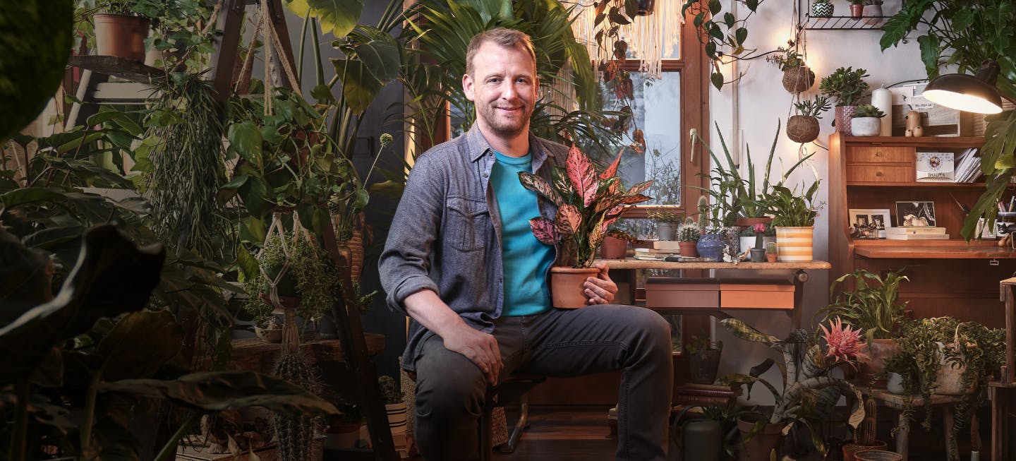 A man living with HIV proudly sitting with his house plants