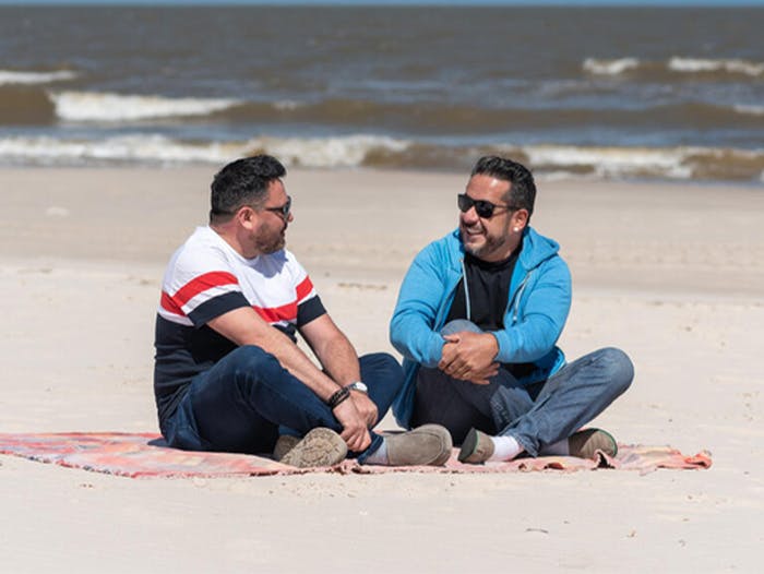 two men sit on beach