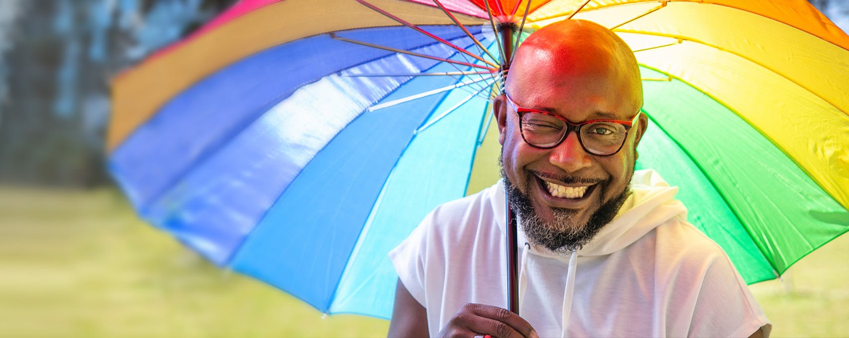 A person smiling with a rainbow umbrella