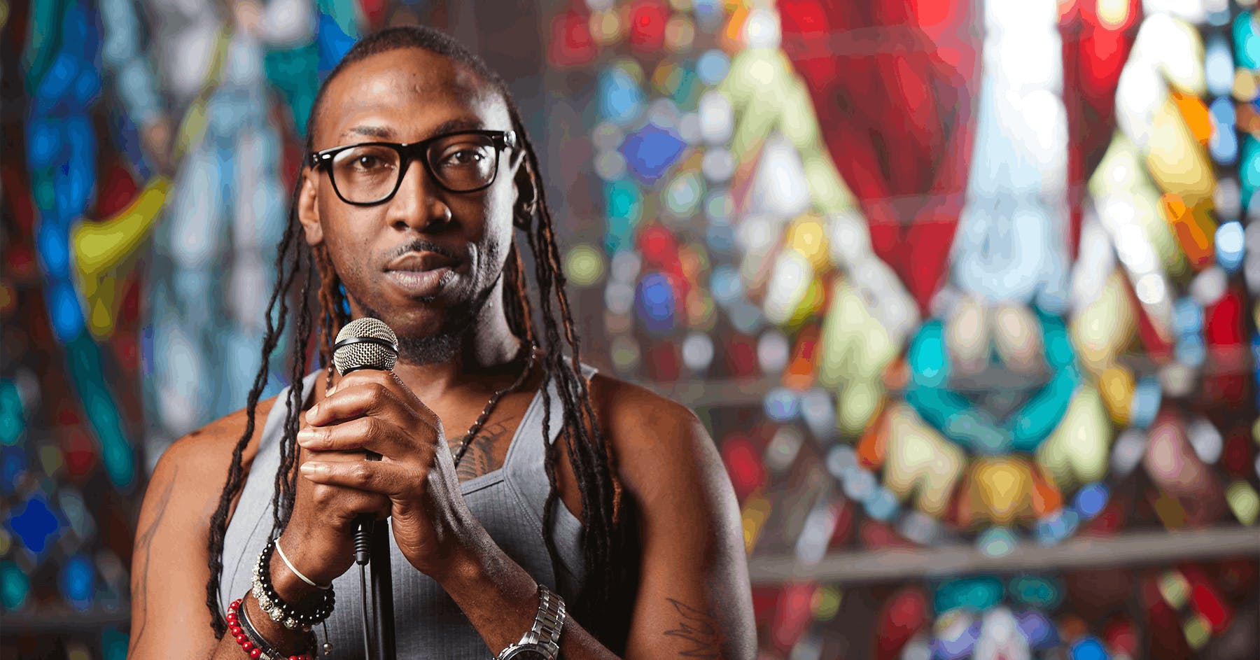 Person with microphone in front of stained glass