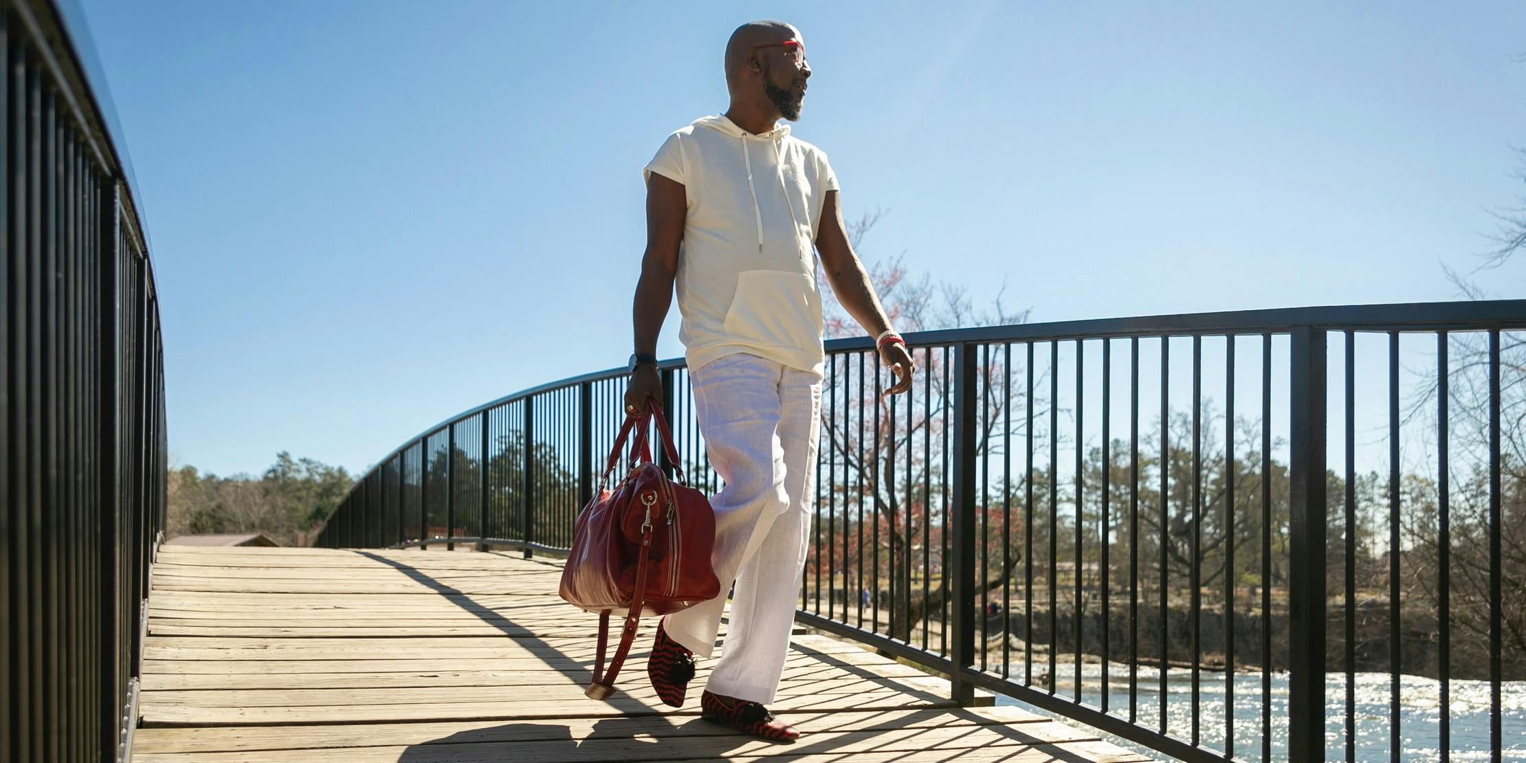 $titleDesktopImage Man holding bag walking across a bridge